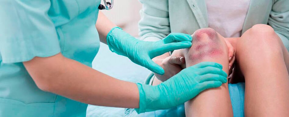 um médico examina uma lesão no joelho